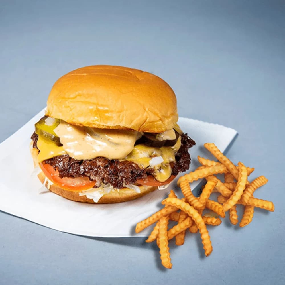 Potato bun, gesmashte Angus beef, American cheese, ijsbergsla, augurk, ui, tomaat en smash saus. Waar alles mee begonnen is.