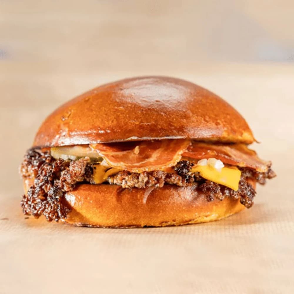 Angus beef, halal bacon en cheese op brioche, met alle toppings en smash saus. Zoet broodje, zoute bacon.
